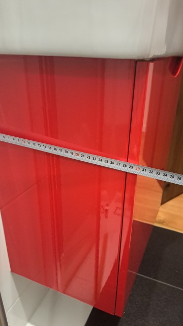 Czerwona szafka łazienkowa z umywalką i kranem